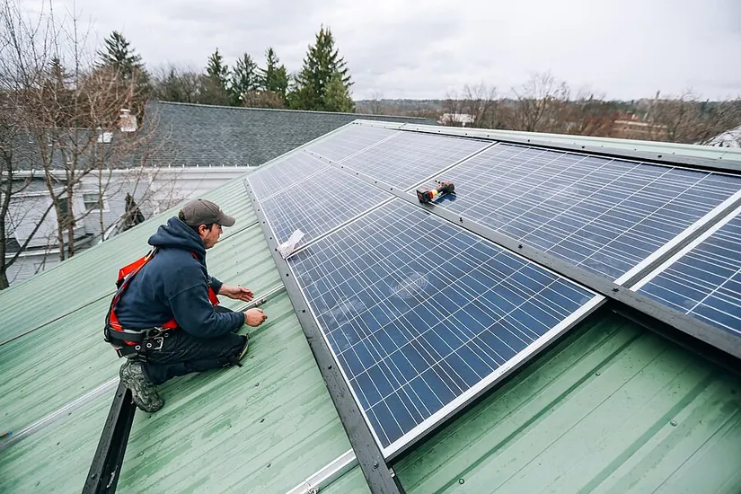 Técnico con arnés montando placas solares en una cubierta metálica